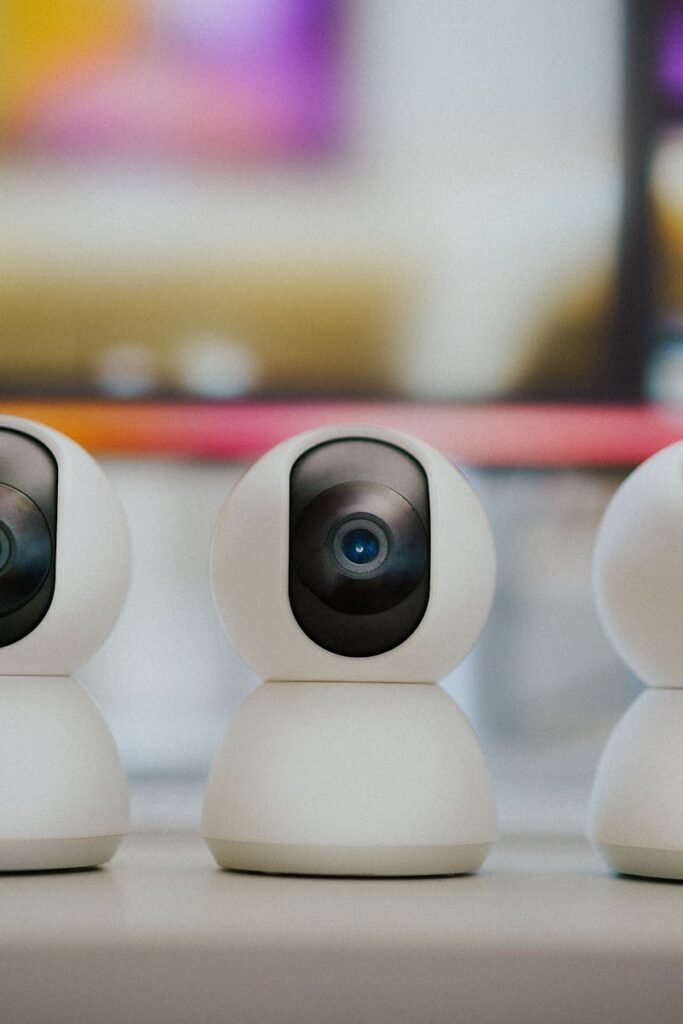 Three modern smart home security cameras placed on a table indoors with a blurry background.